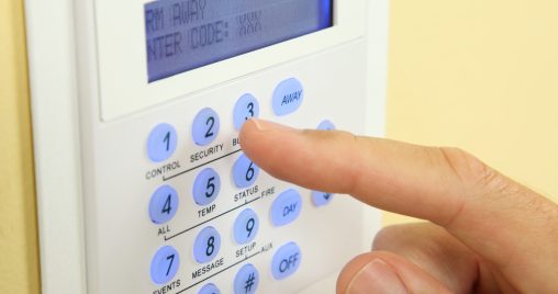 Close up of a security alarm keypad with person arming the system.